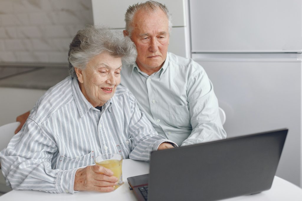 Elegant old couple sitting at home and using a laptop