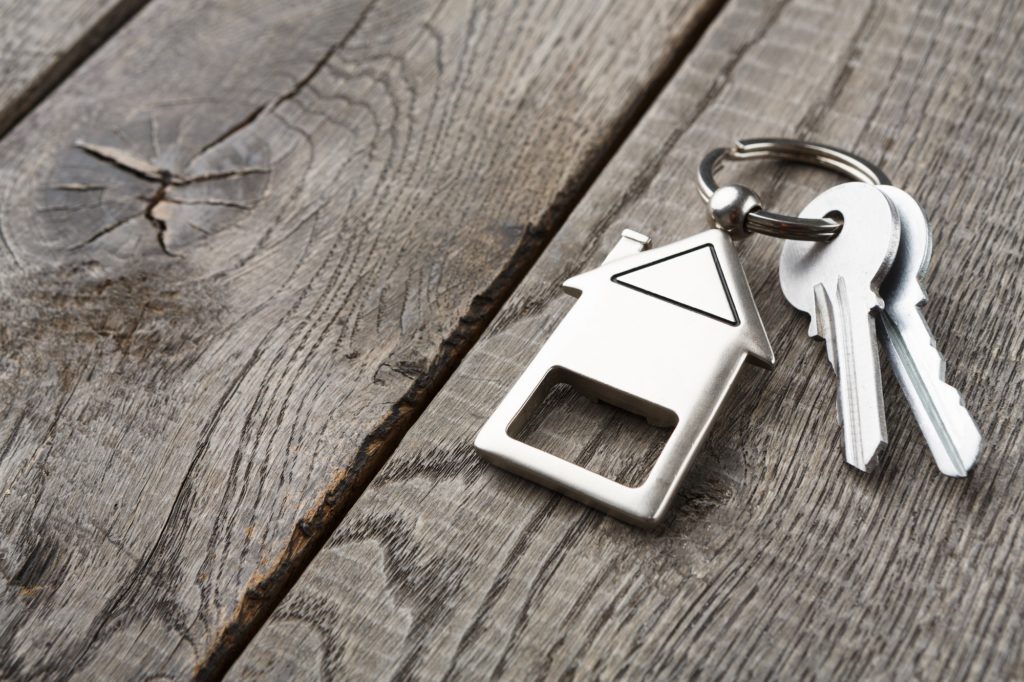 Bunch of keys with house shaped keychain on rustic wood
